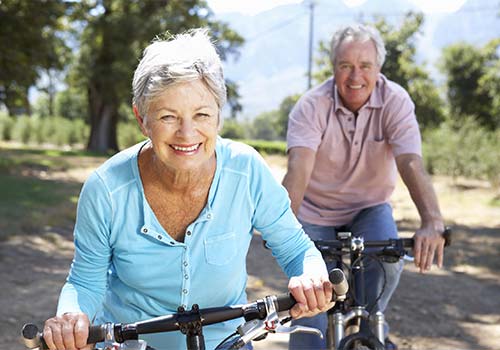 elderly couple smiling and riding bikes together