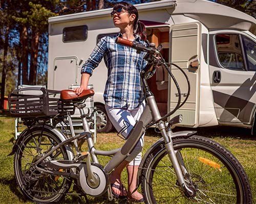 woman standing next to an electric bike outside of a small RV